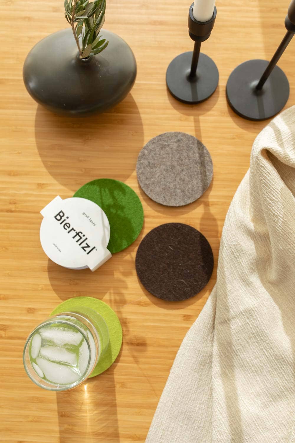Set of coasters on a wooden surface with a glass of water and a bottle.