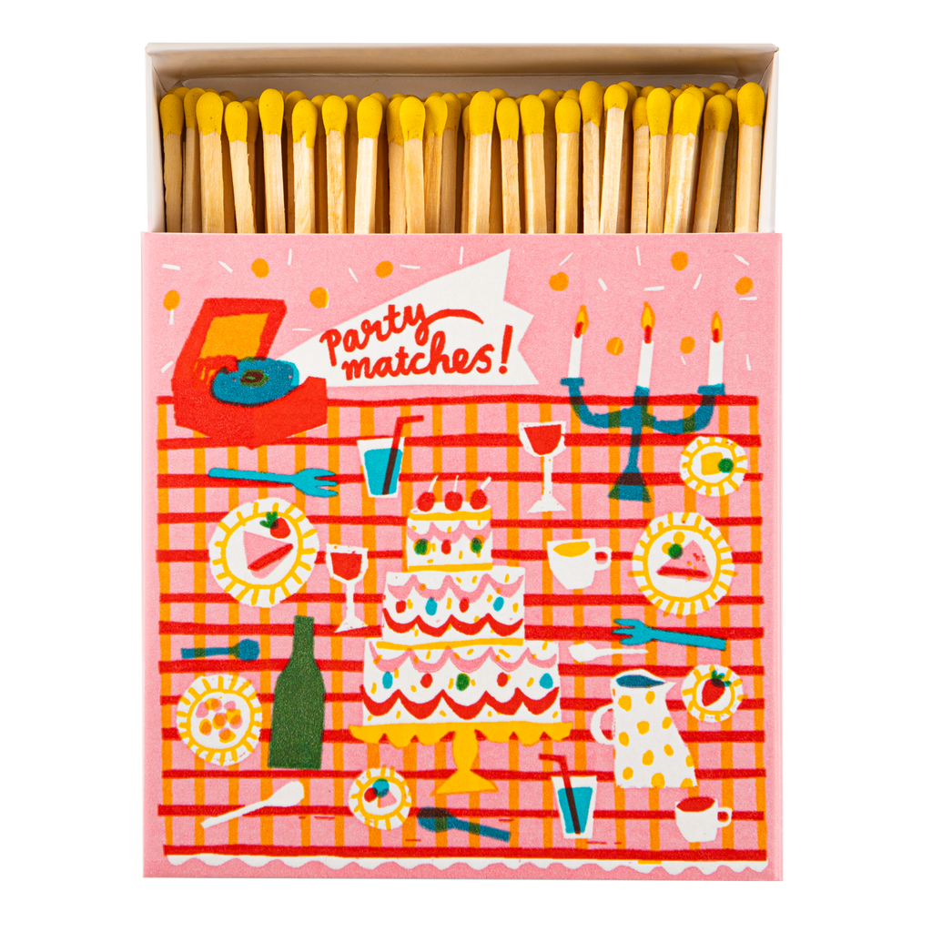 A novelty matchbox with a pink and red party-themed illustration on the front, shown open with yellow-tipped matches inside. The front reads 'Party matches!' and features colorful party icons like a cake, candelabra, drinks, and tableware.