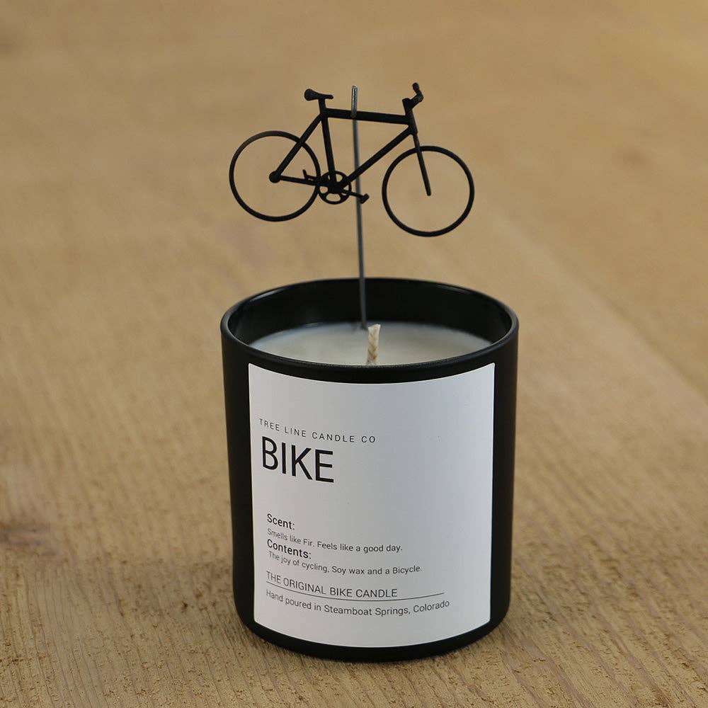 Candle with a bicycle-themed candle stick on a wooden surface