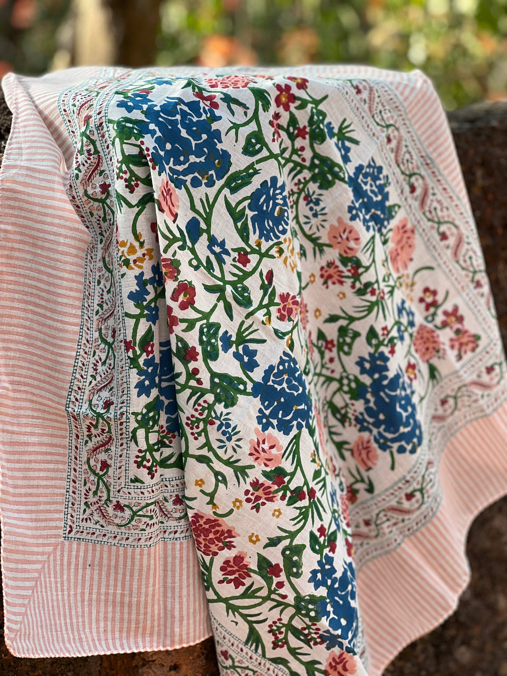 Floral patterned fabric draped over a chair with a blurred natural background