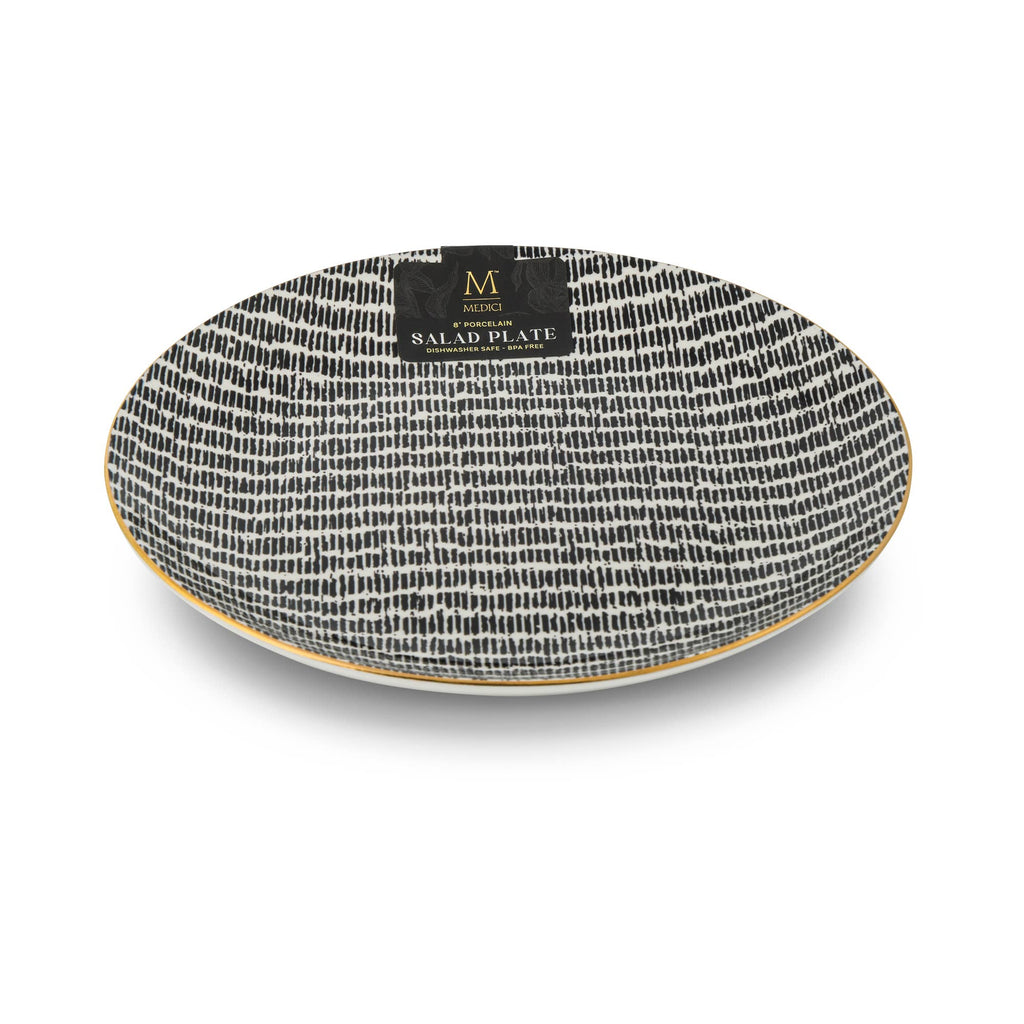 An oval ceramic salad plate with a black and white textured brushstroke pattern and a gold rim, featuring a black brand label on top.