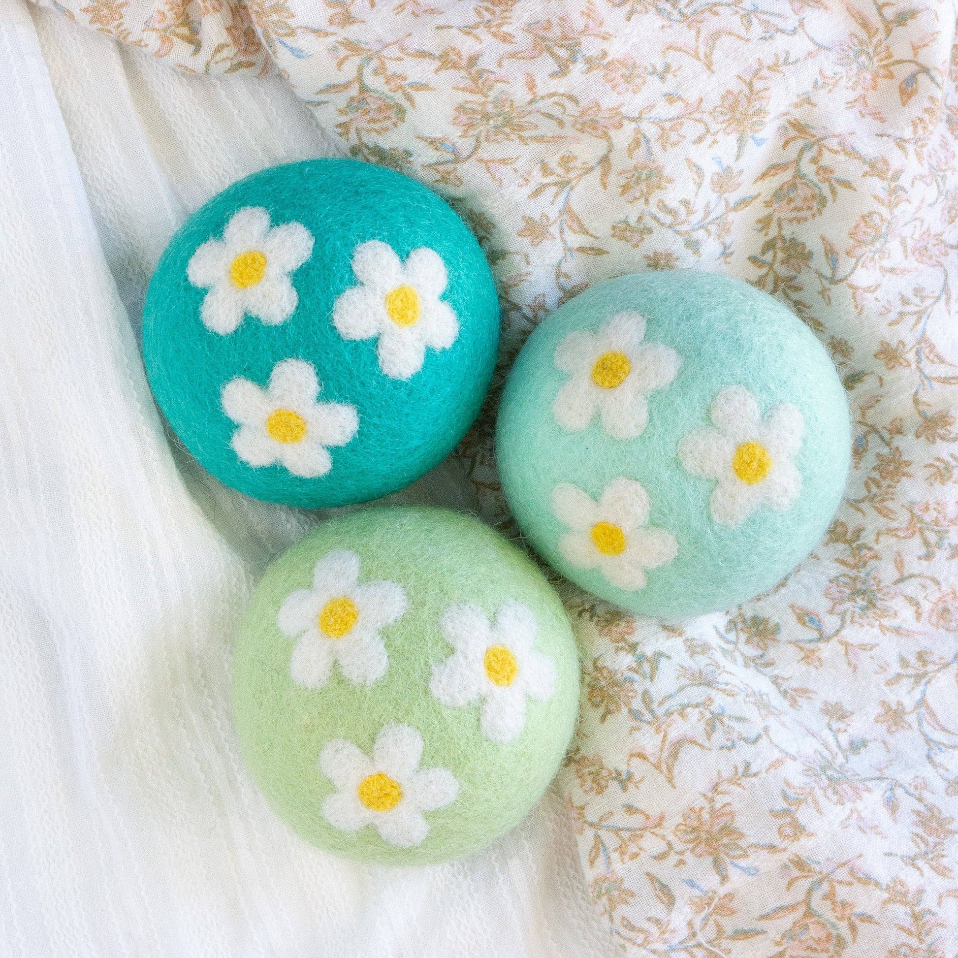 Three round bath bombs with floral designs on a textured fabric background