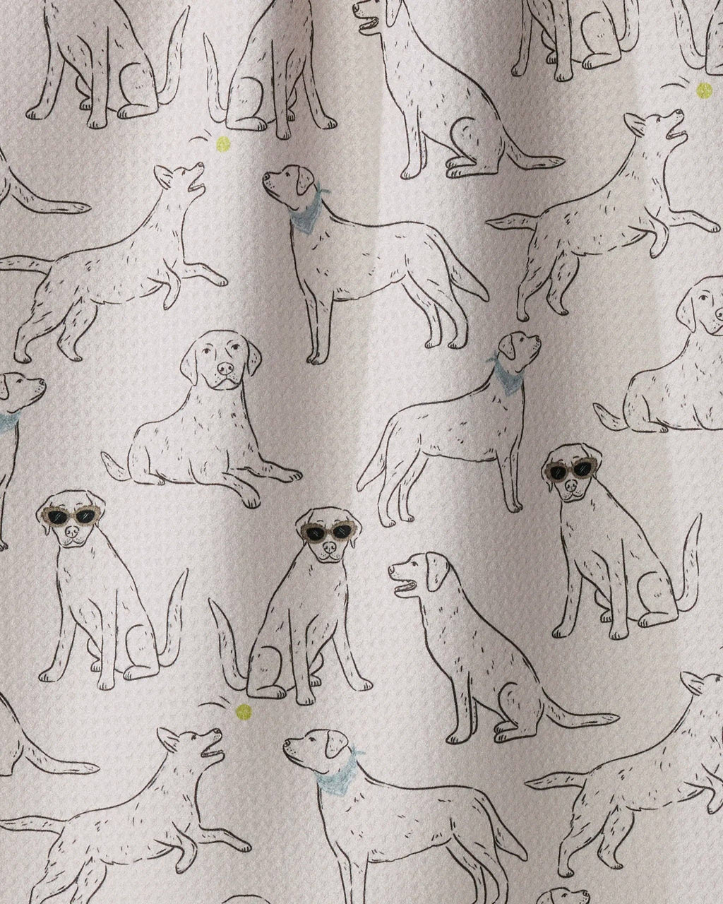 A close-up of a fabric surface featuring an all-over print of illustrated dogs in black line drawings, with a few small blue and yellow accents, on a light warm beige background.