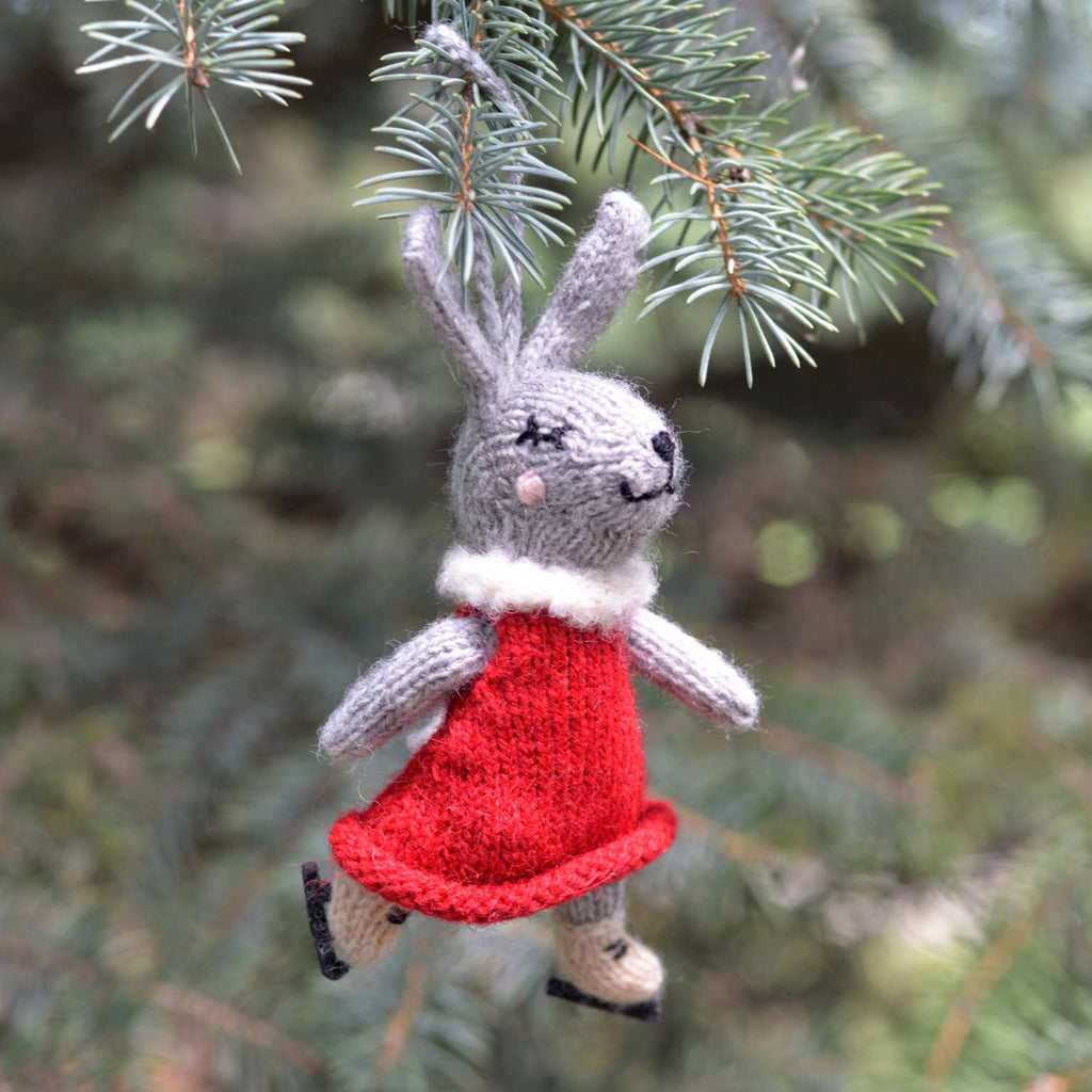 Knitted mouse ornament in a red dress hanging on a tree branch