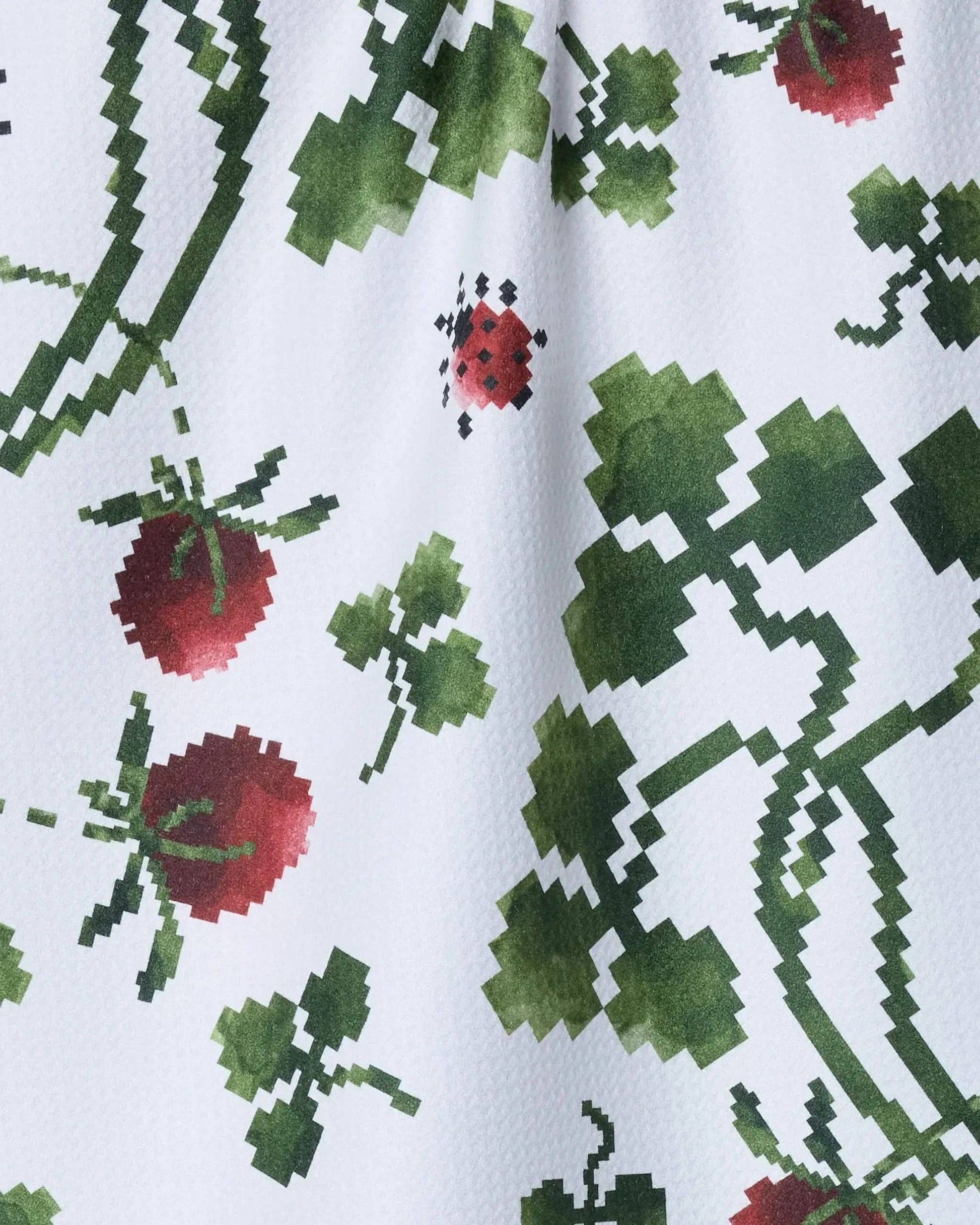 Close-up of a fabric with pixelated green and red floral pattern on a white background