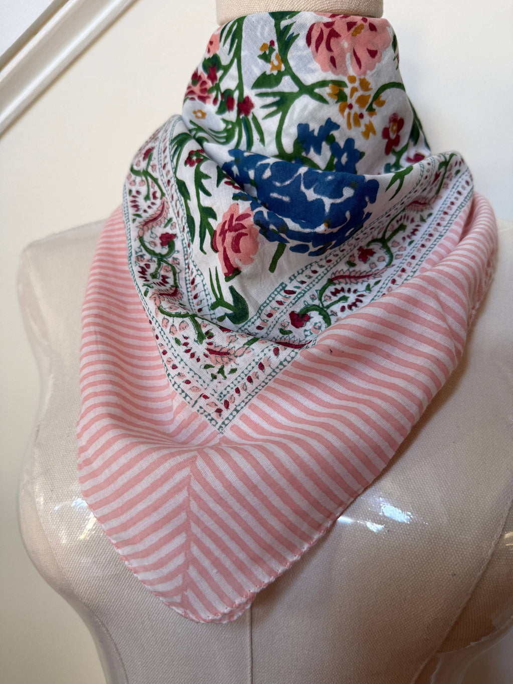 Scarf with floral and striped patterns draped over a mannequin head.