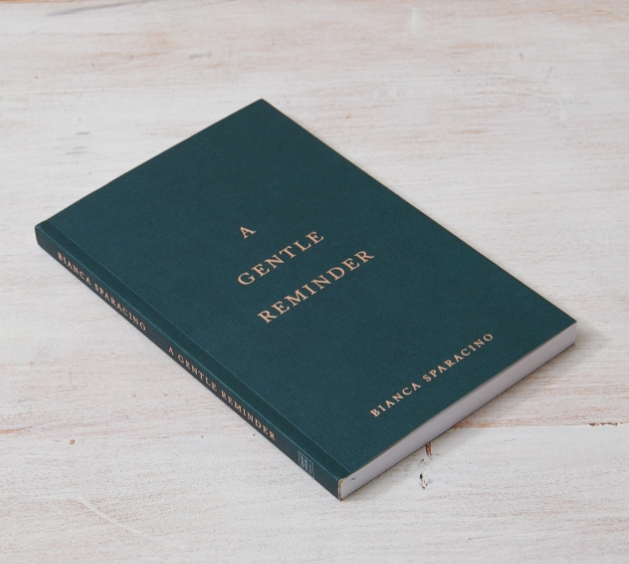 Book titled 'A Gentle Reminder' by Bianca Sparacino on a light wooden surface