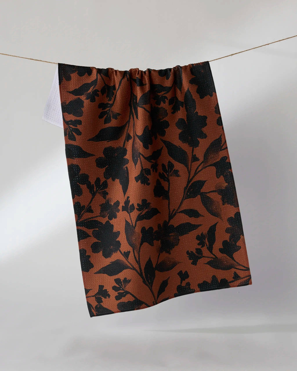 Floral patterned fabric hanging on a line against a white background