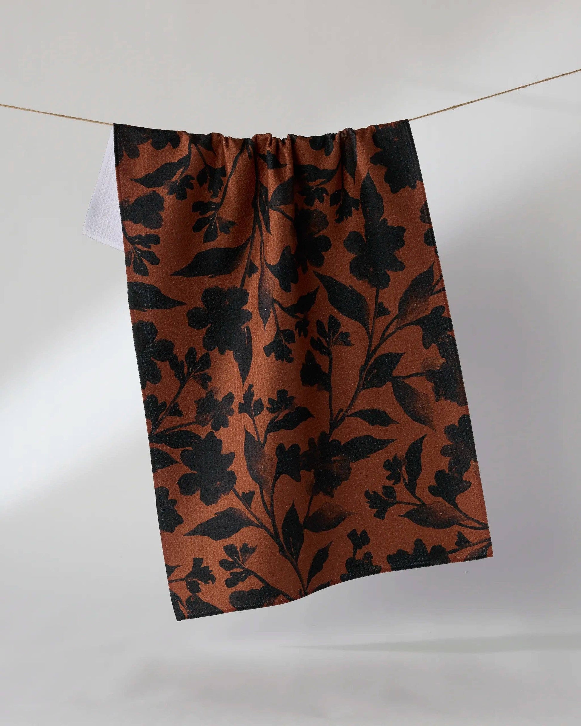 Floral patterned fabric hanging on a line against a white background
