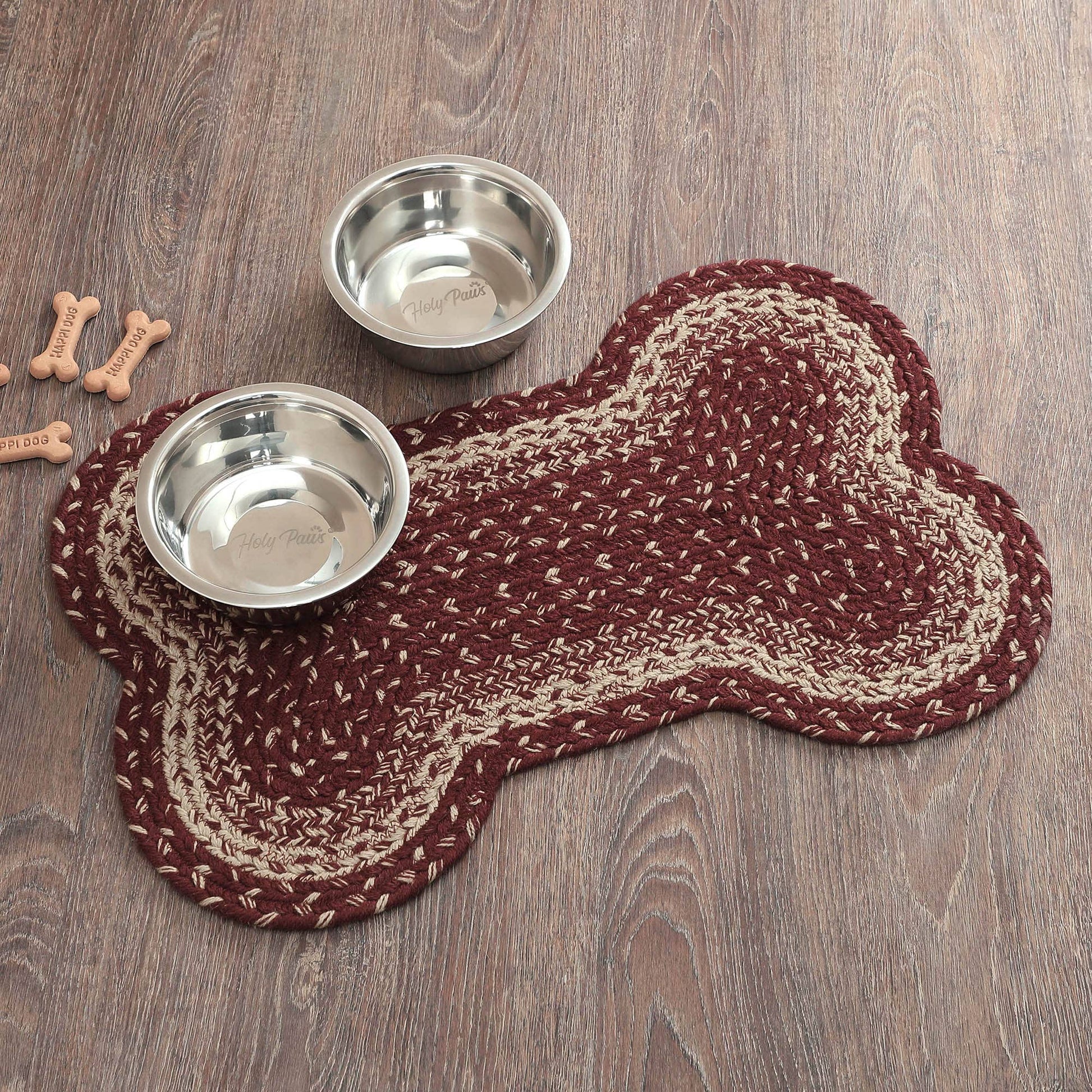 Two metal dog bowls on a braided dog bone mat on a wooden floor.