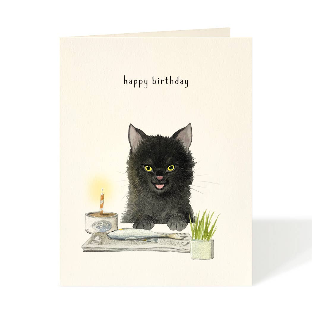 Birthday card with a black kitten, fish, candle, and plant on a table.