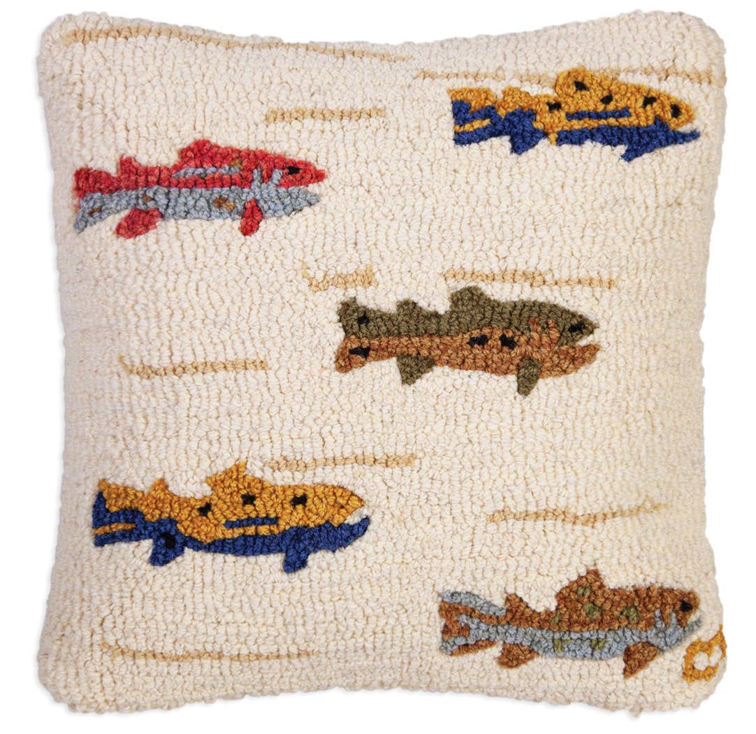 A square, textured throw pillow in cream with a hand-hooked fish pattern in red, blue, yellow, brown, and gray.