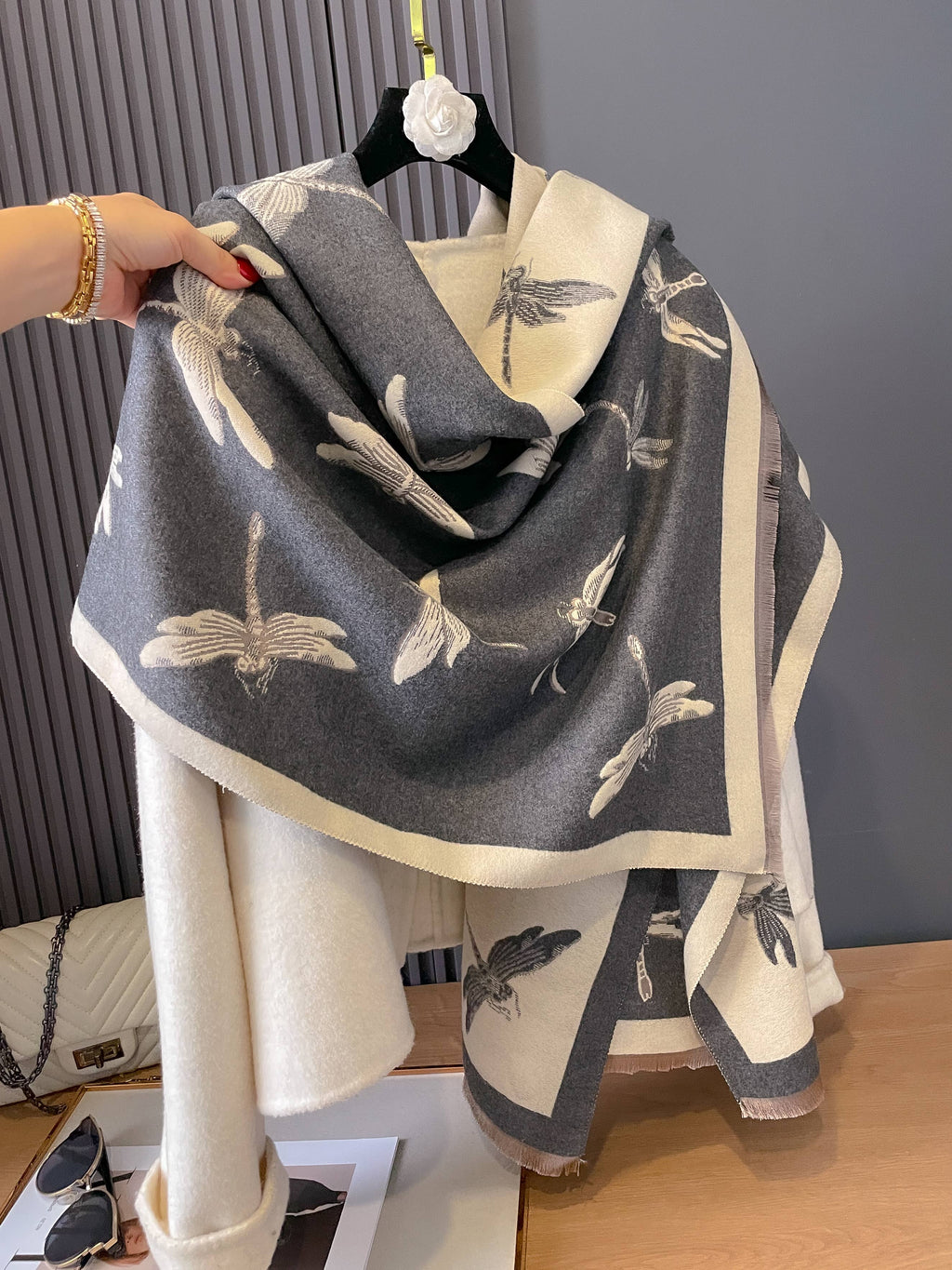 Gray scarf with bird pattern draped over a white garment on a wooden surface.