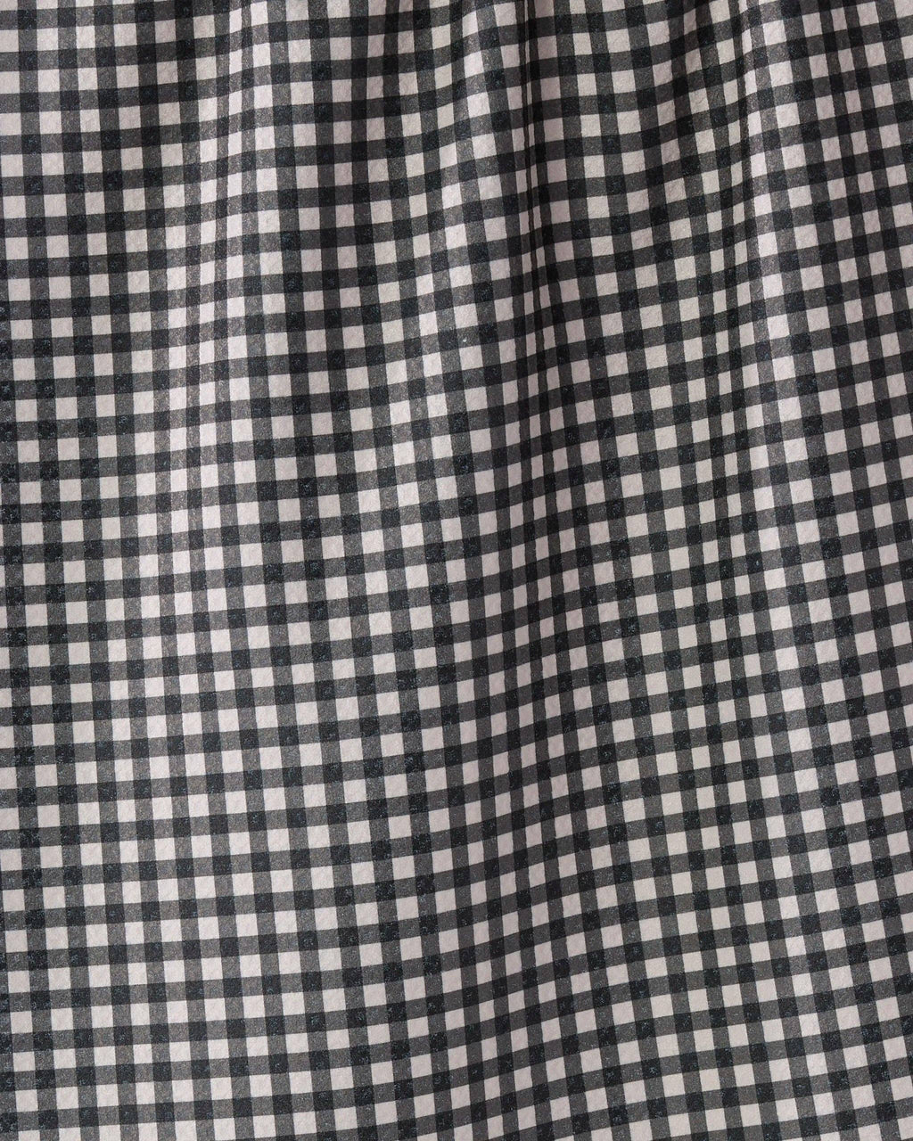 A close-up of a black and white gingham checkered fabric with a soft, draped texture.