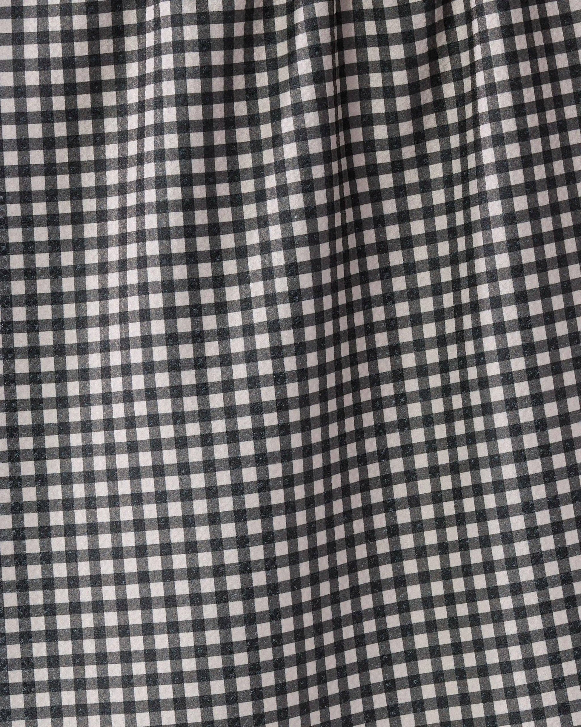 A close-up of a black and white gingham checkered fabric with a soft, draped texture.