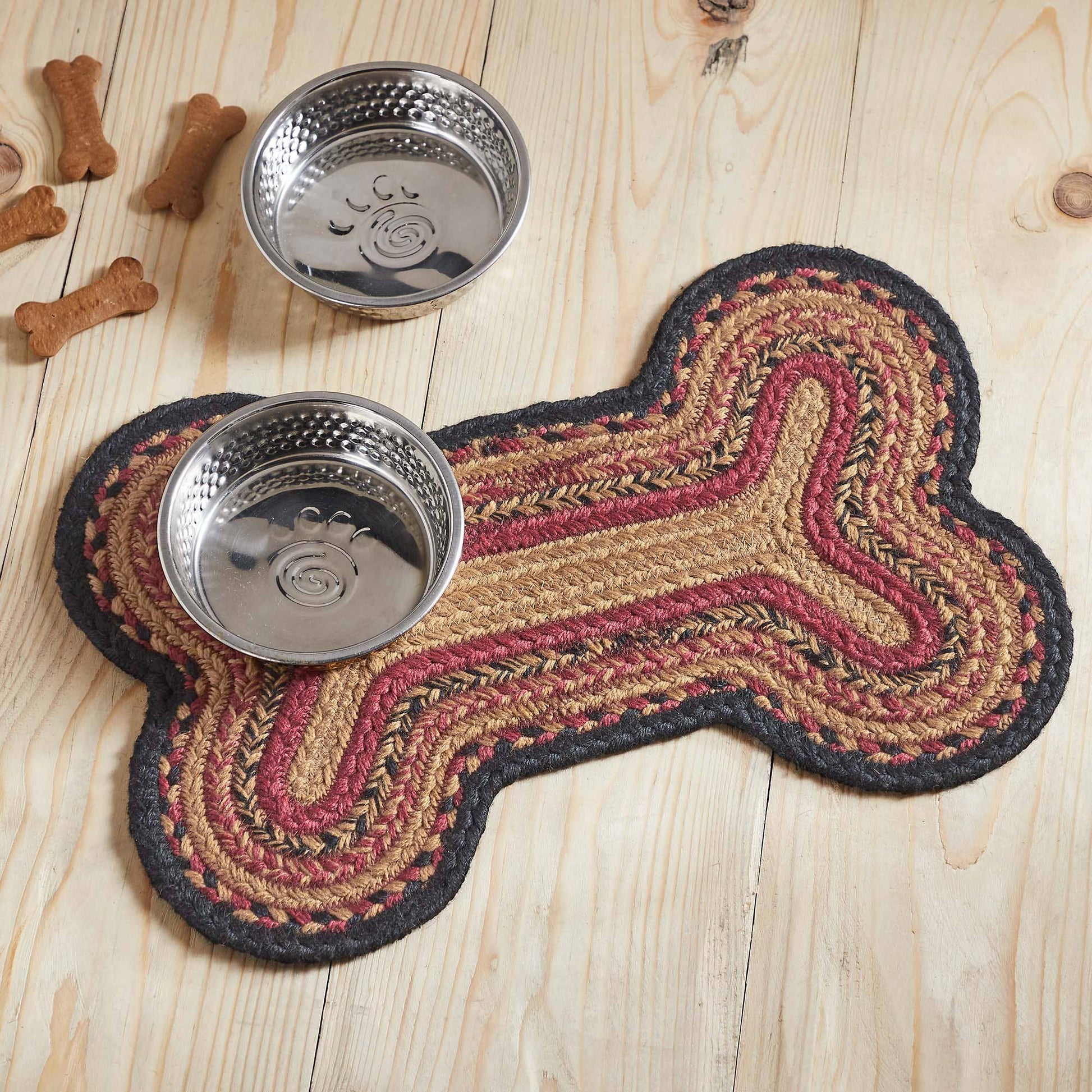 Dog bone-shaped mat with two metal bowls on a wooden surface.