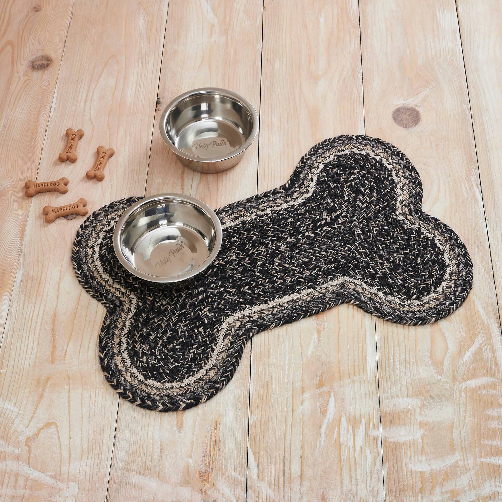 Dog bone-shaped mat with two metal bowls on a wooden floor.