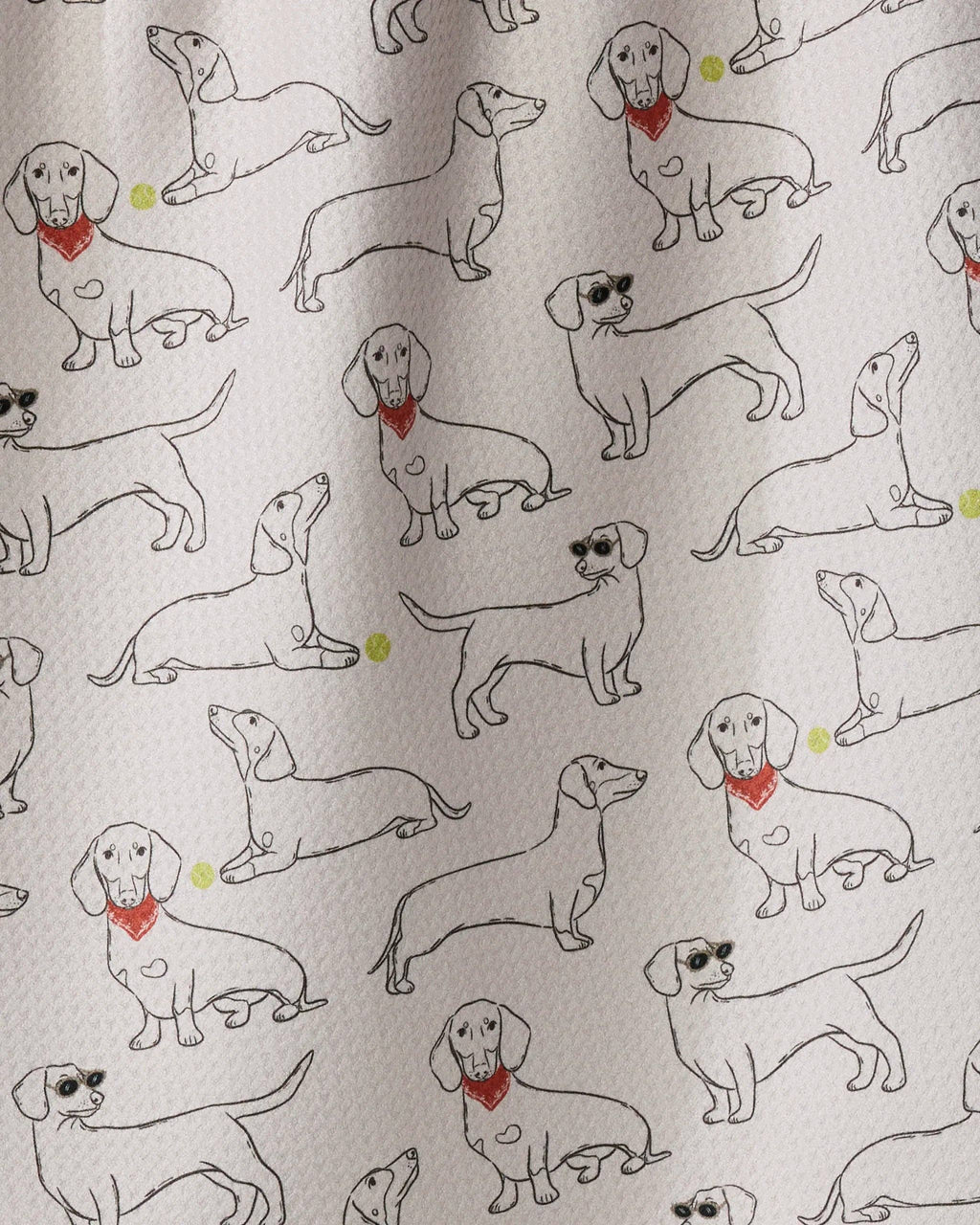 A close-up of a fabric or paper surface with an allover print of dachshund illustrations. The dogs are drawn in black outline with small red bandanas and a few have tiny yellow accents.