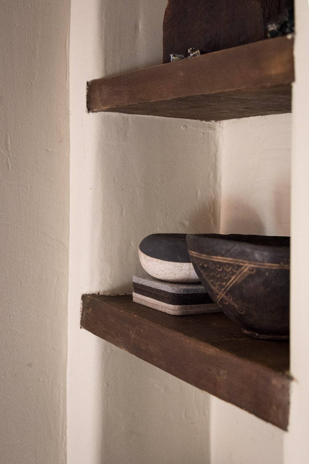 Wooden shelves with ceramic bowls against a plain wall