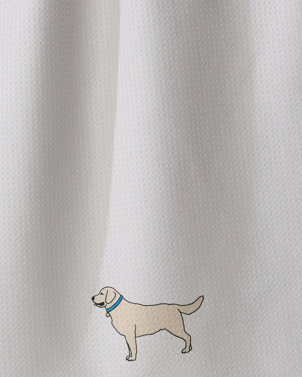 Close-up of a white textured fabric with a small embroidered dog wearing a blue collar near the lower left area.