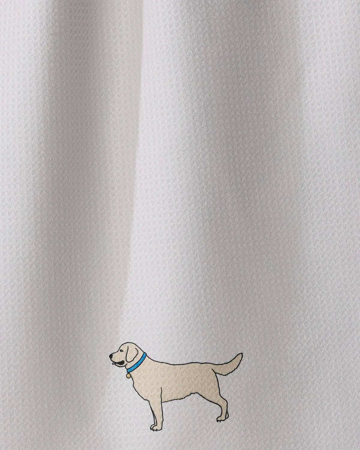 Close-up of a white textured fabric with a small embroidered dog wearing a blue collar near the lower left area.
