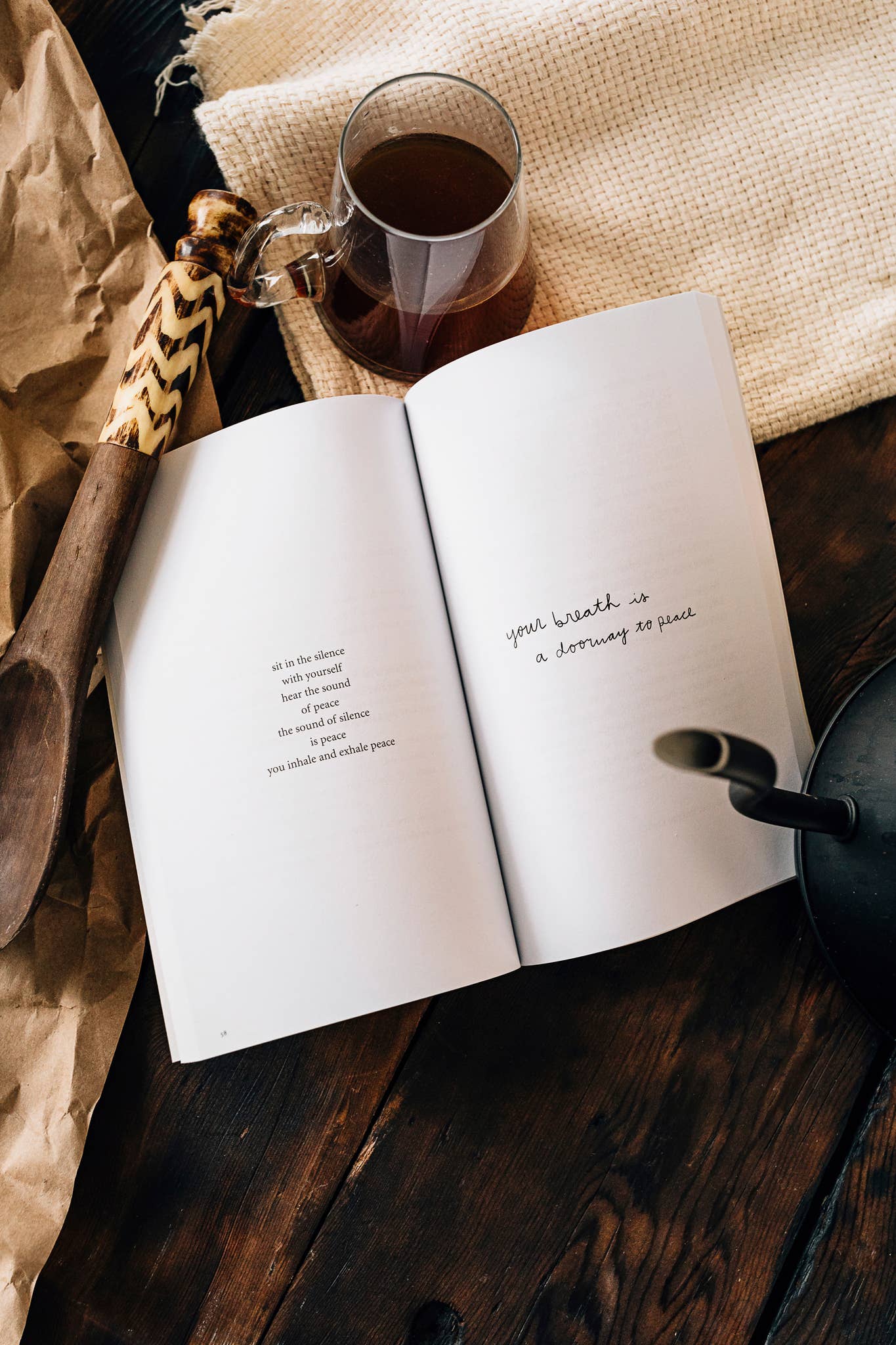 Open book with a quote, mug of coffee, and decorative items on a wooden surface