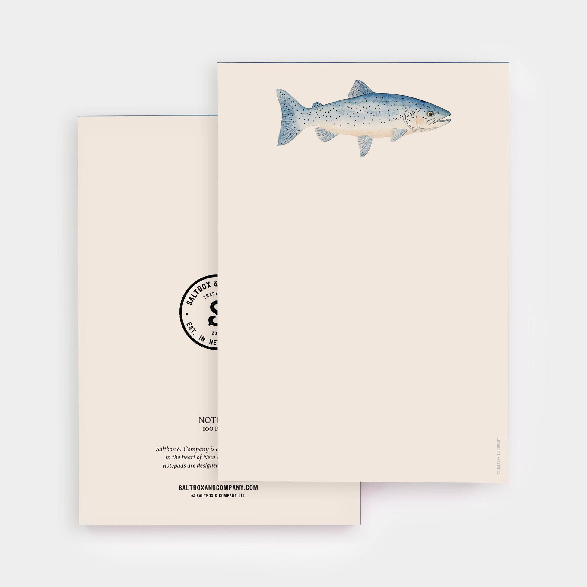 A minimalist stationery set featuring a cream-colored card with a detailed blue-gray trout illustration and a matching cream envelope with a black circular stamp design.
