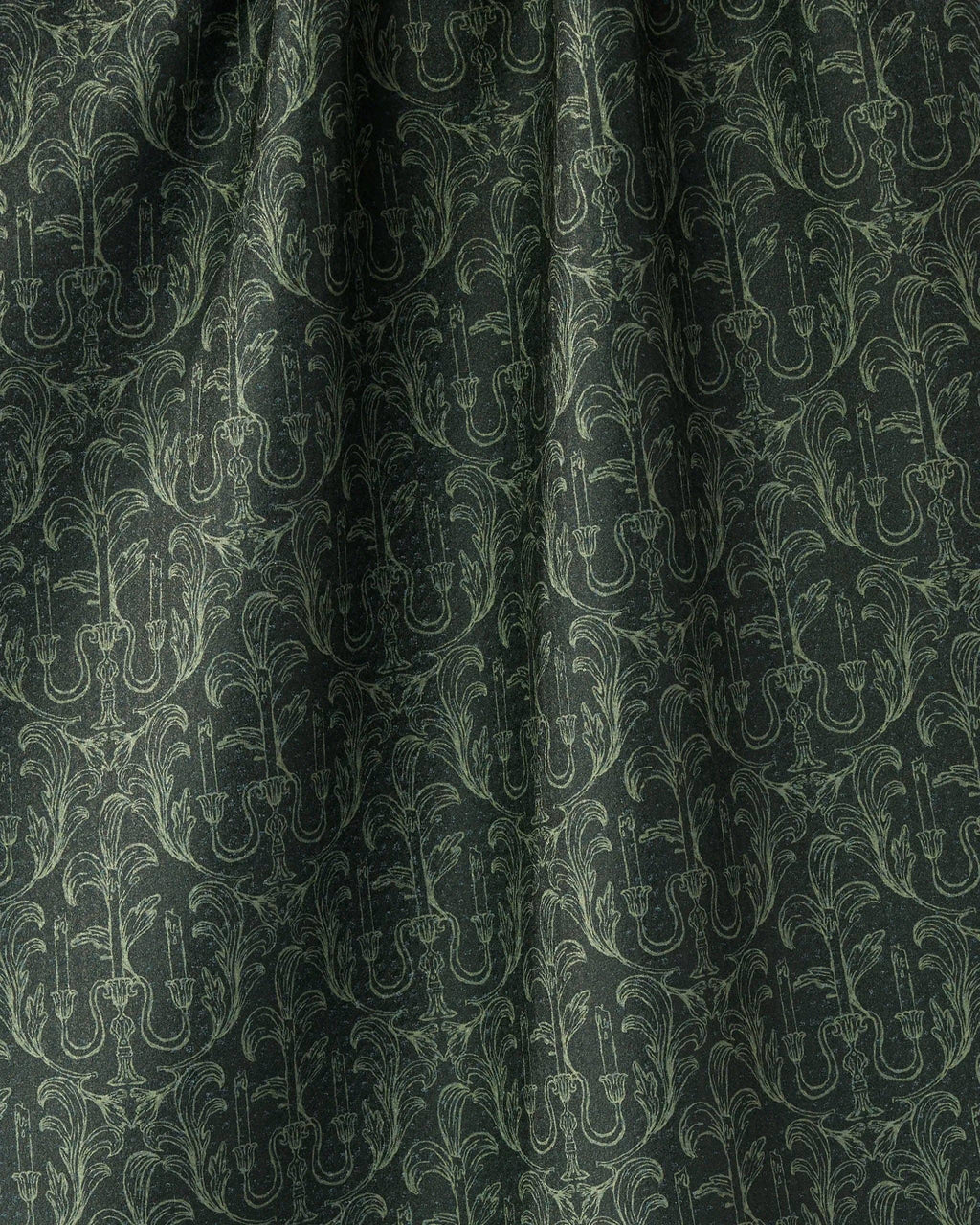 Dark green fabric with a repeating light sage green damask pattern of candelabras and ornate scrollwork.