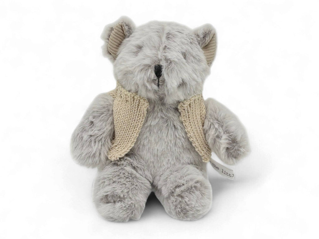 Gray teddy bear with a beige knitted scarf on a white background