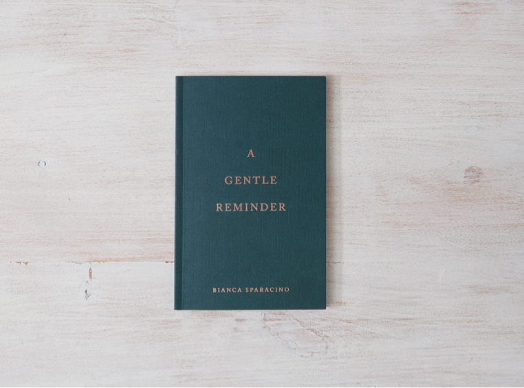 Book titled 'A Gentle Reminder' by Bianca Sparacio on a light wooden surface