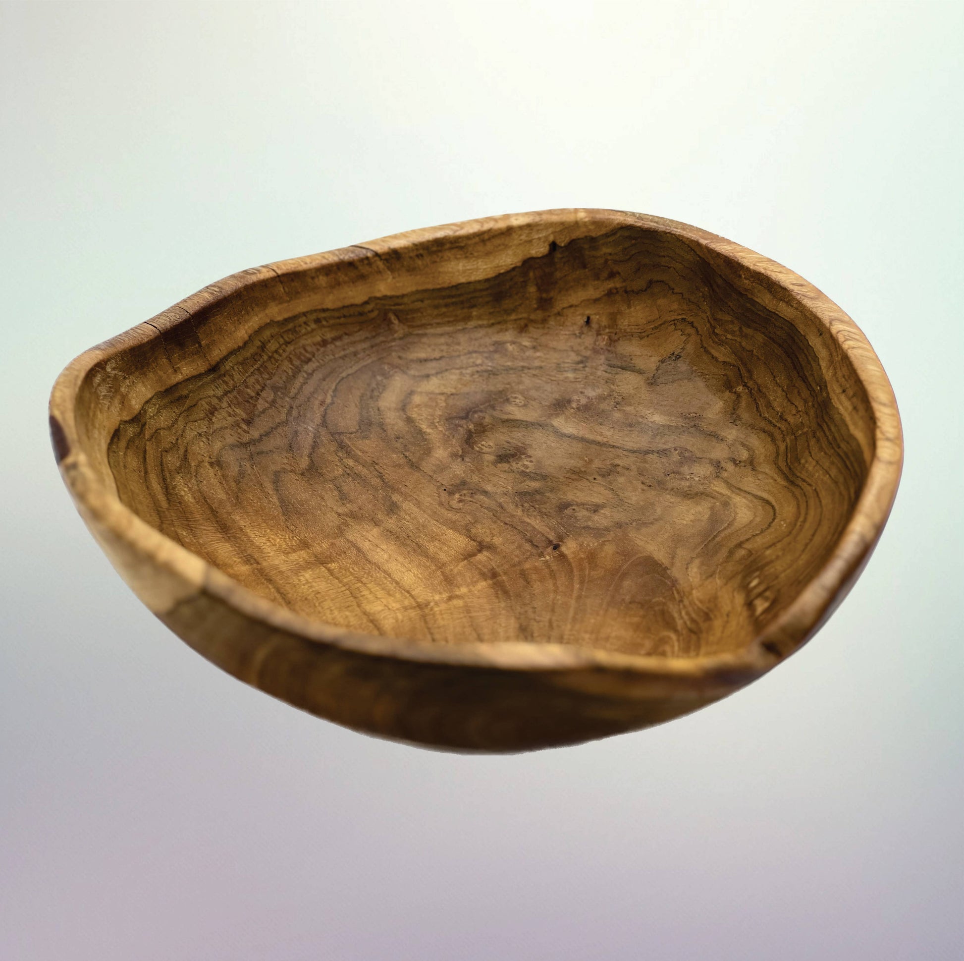 A rustic handcrafted wooden bowl with a natural irregular edge and prominent wavy wood grain patterns, shown against a light gray gradient background.