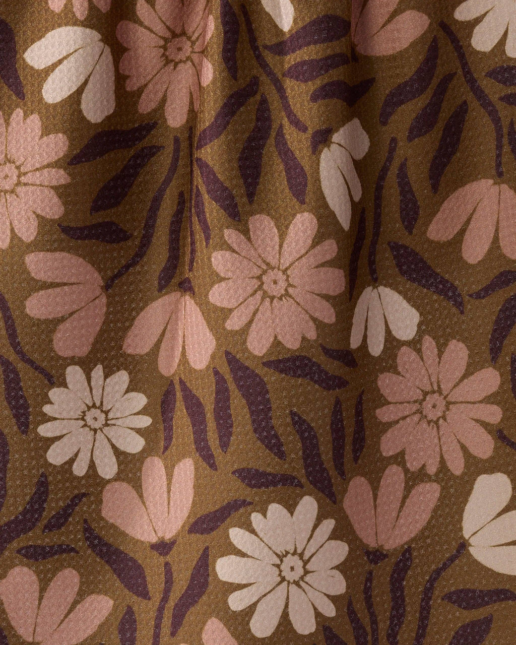A close-up of a fabric or wallpaper pattern featuring stylized pink and off-white flowers with dark purple leaves on a warm brown background.