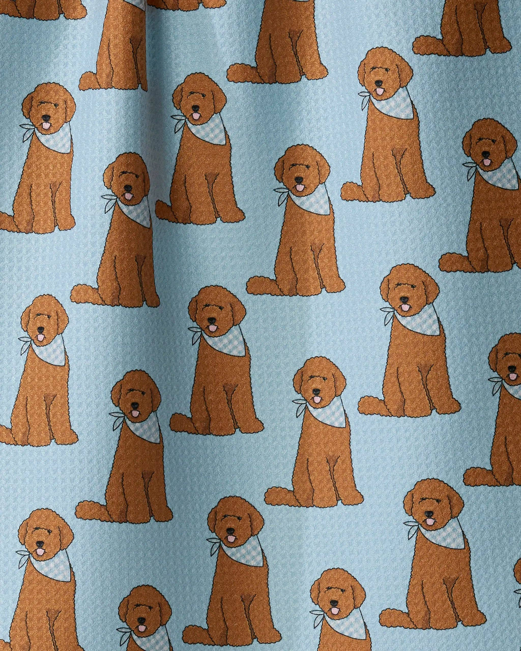 A close-up of a light blue fabric with a repeating pattern of golden retriever dogs wearing white bandanas.