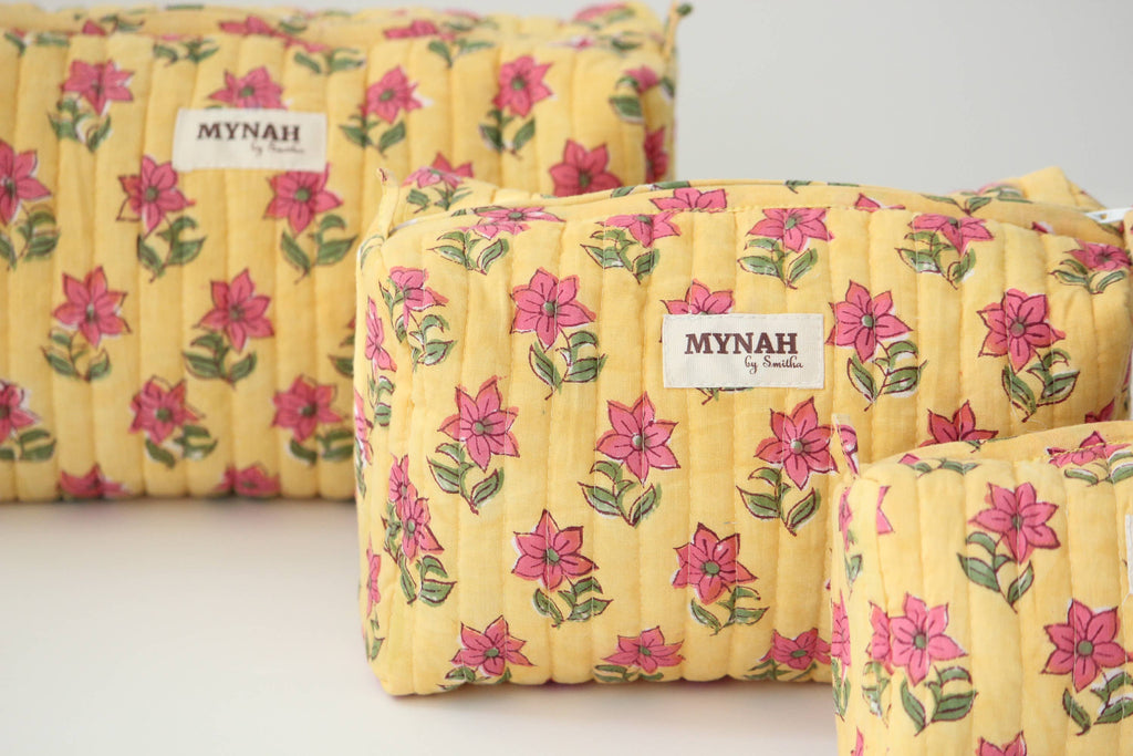 Yellow floral-patterned bags with 'MYNAH' branding on a light background