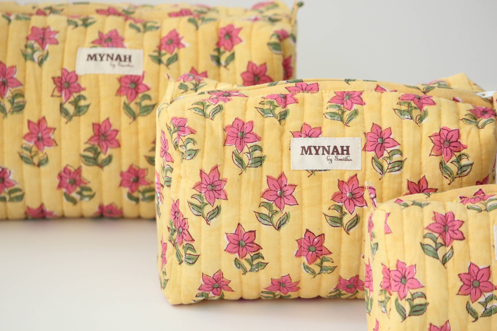 Yellow floral-patterned bags with 'MYNAH' branding on a light background