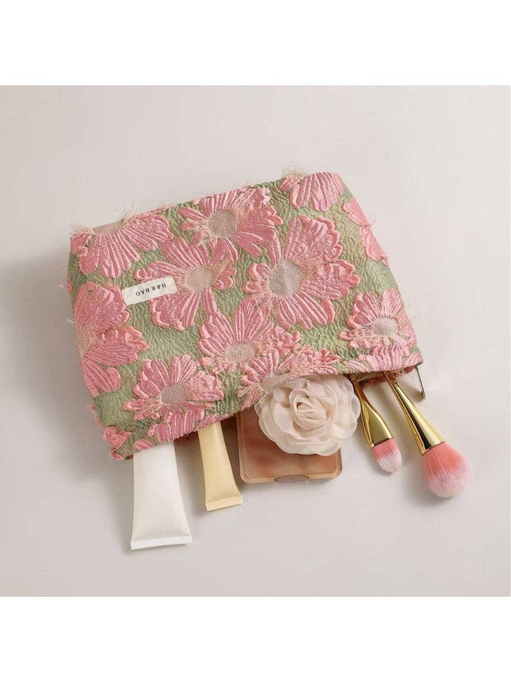 Floral makeup bag with cosmetic items on a light gray background