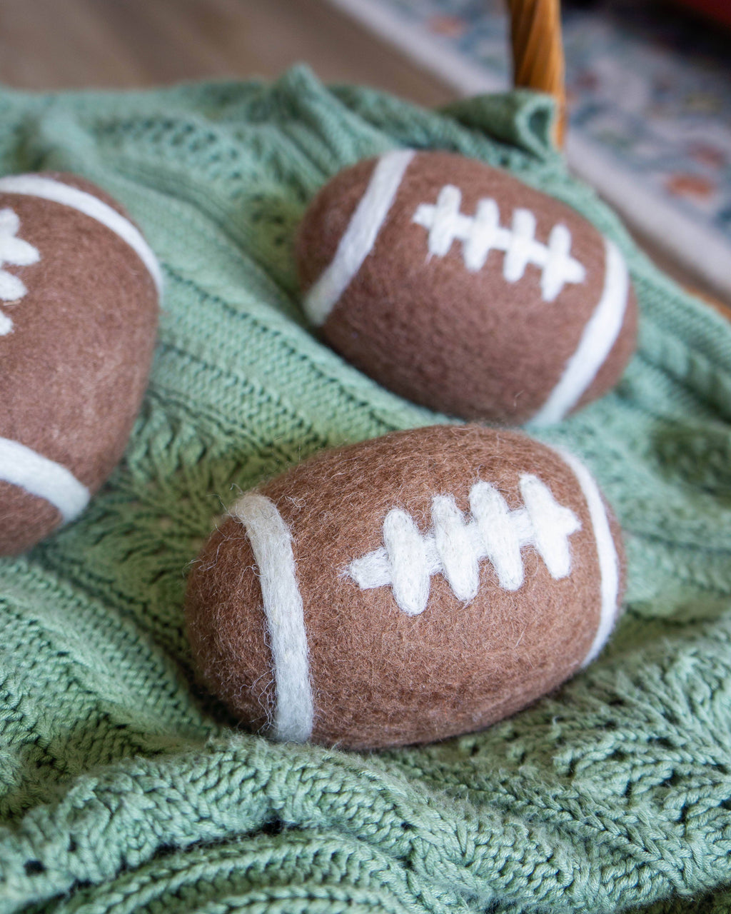 Three brown and white football-shaped objects on a green textured surface.