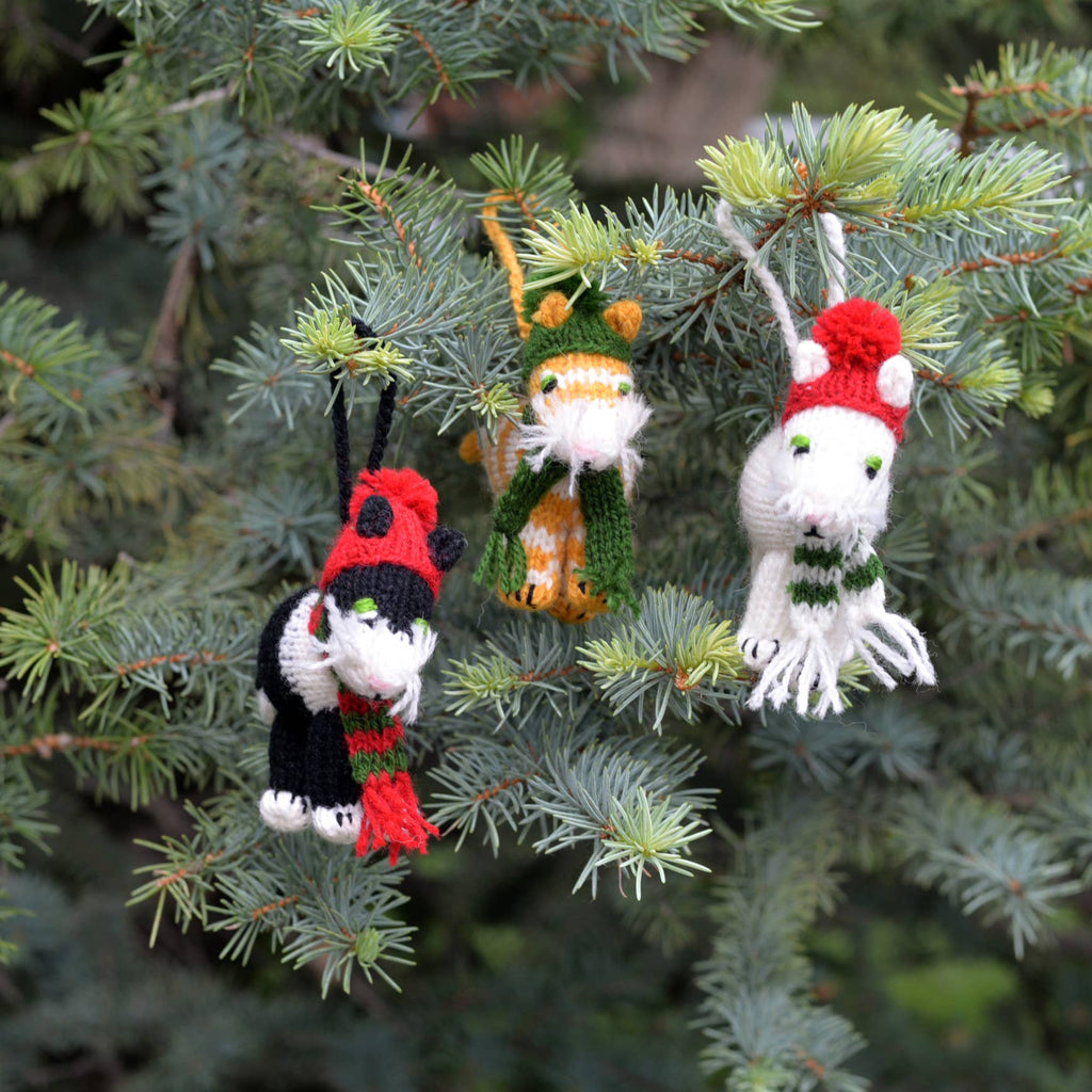 Three knitted cat ornaments on a Christmas tree.