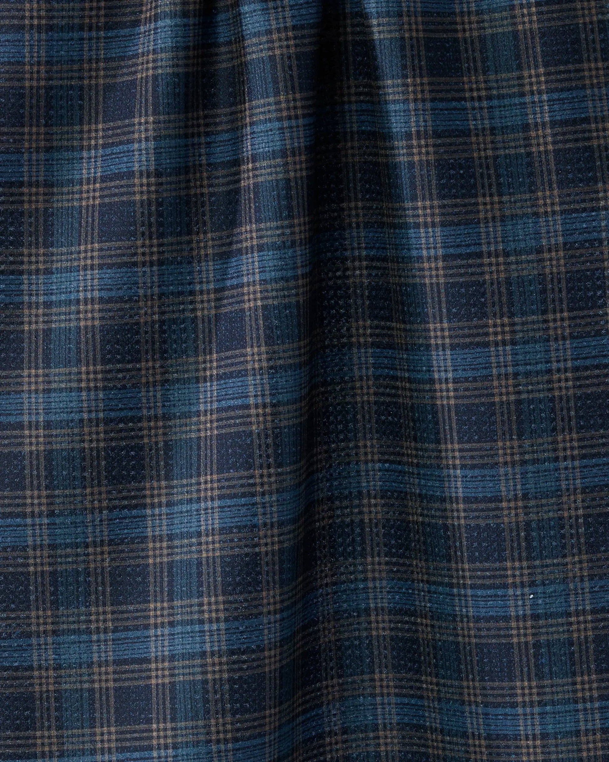 A close-up of a plaid fabric pattern in navy blue, medium blue, and beige, showing the texture and weave of the material.