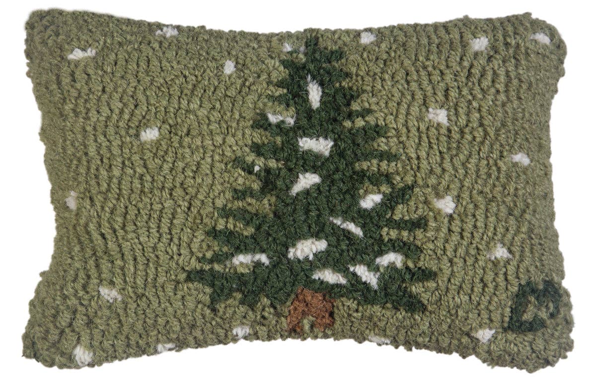 A rectangular hand-hooked throw pillow featuring a dark green pine tree with white snow accents on an olive green textured background.
