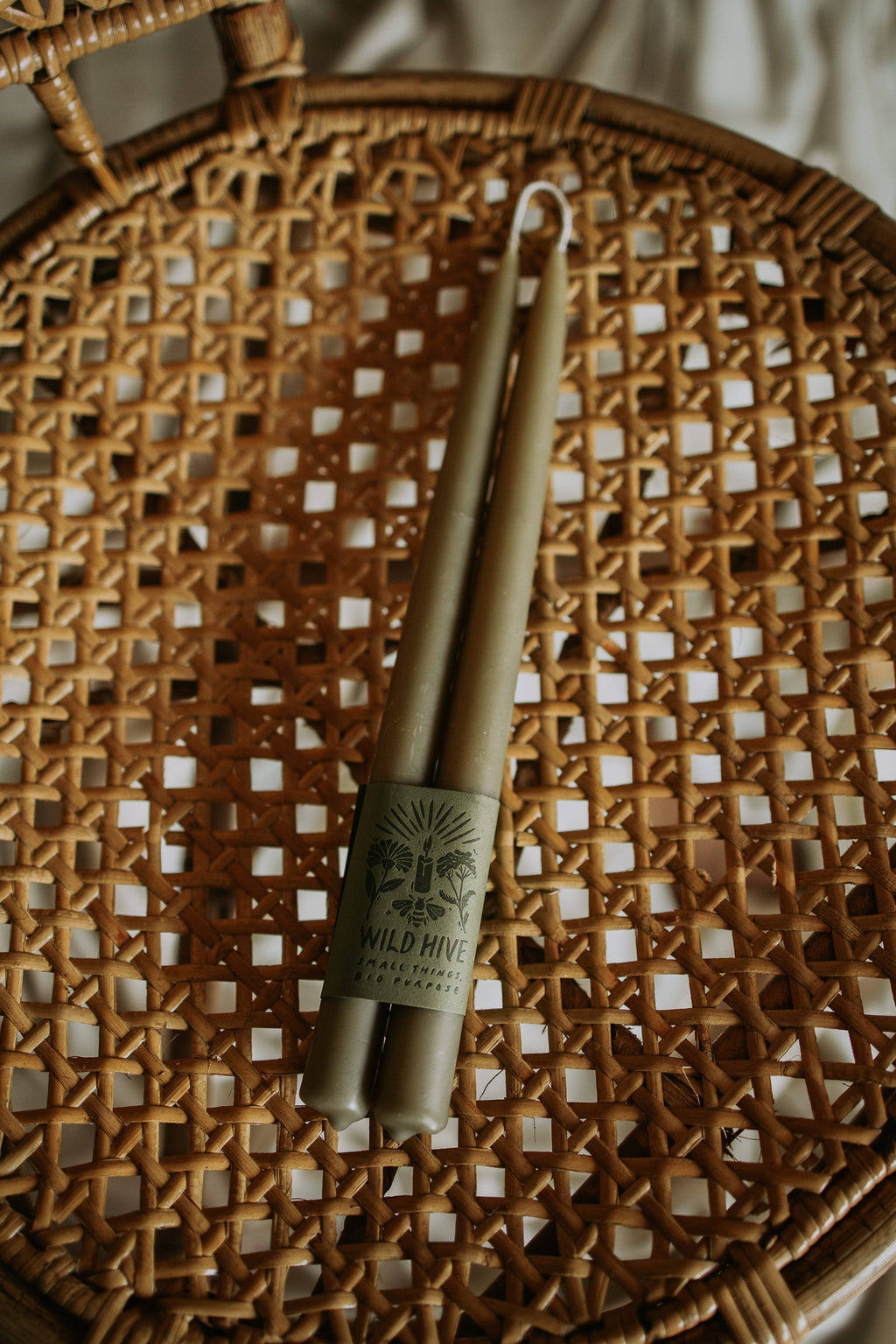 Two candles with a label on a woven surface