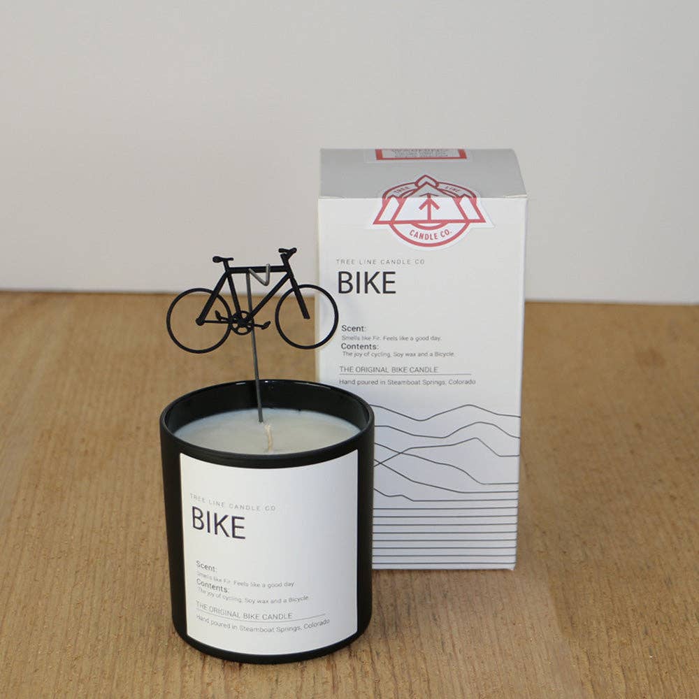 Candle with 'BIKE' label and packaging on a wooden surface
