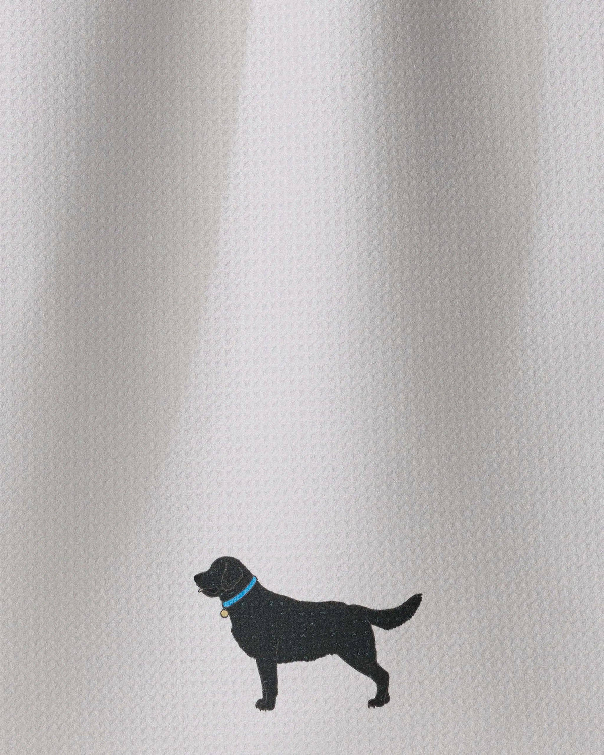 A close-up of a white textured fabric with a small black dog silhouette wearing a blue collar near the bottom center.