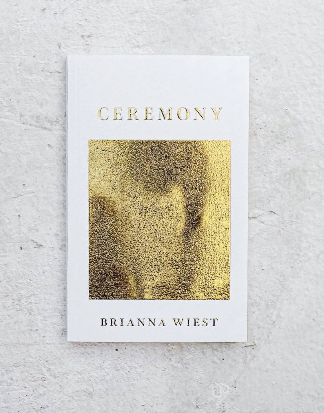 Book titled 'Ceremony' by Brianna Wiest with gold cover on a light gray background