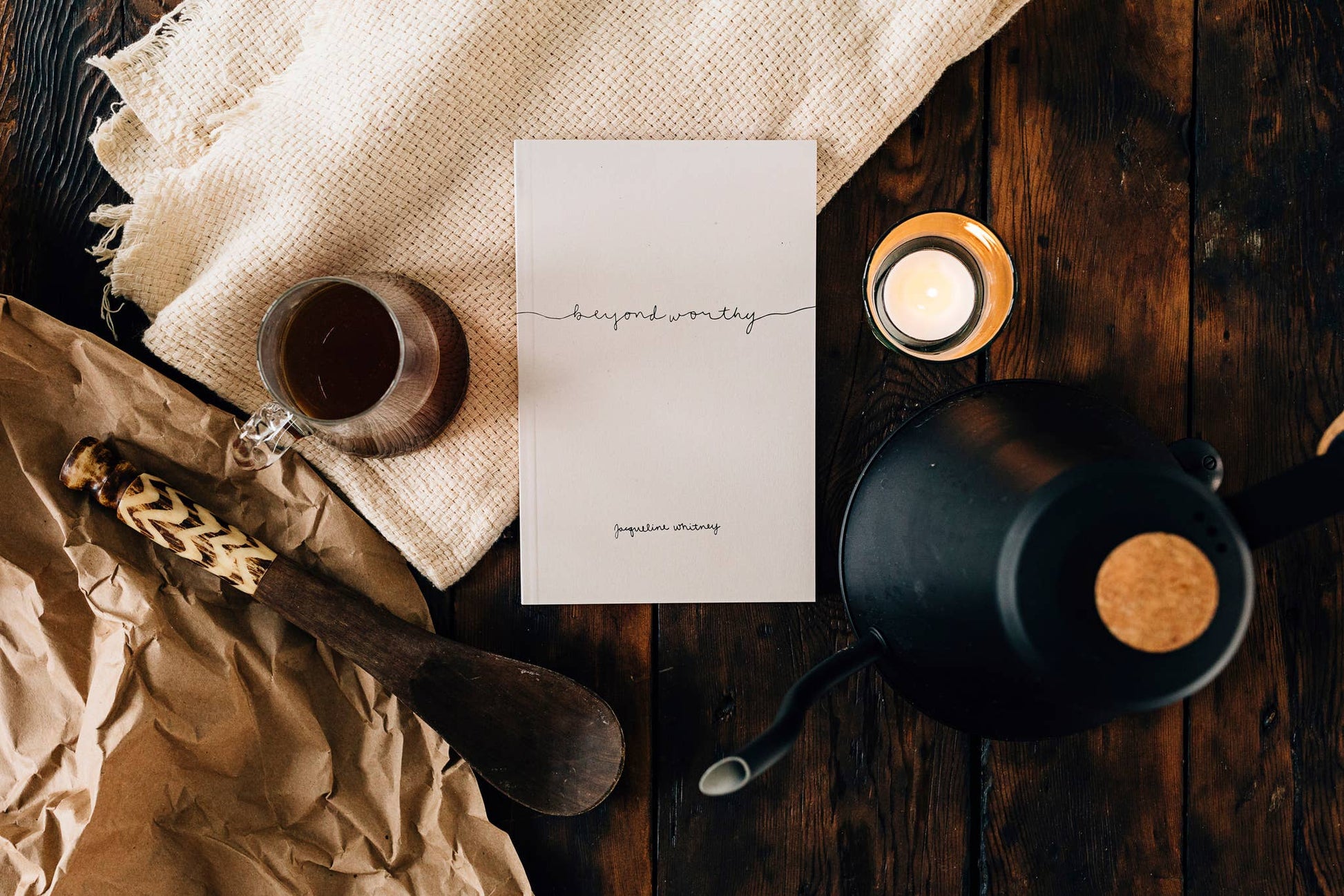 Tea-making setup with a teapot, tea cup, and card on a wooden surface.