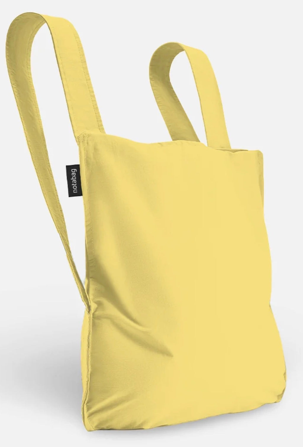 A light yellow fabric tote bag with two shoulder straps and a small black brand tag on the side, shown against a plain light gray background.