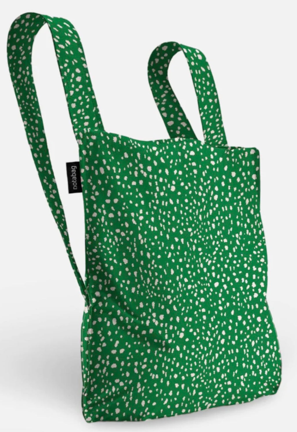A green fabric tote bag with a white speckled pattern, featuring two shoulder straps and a small black brand tag on the side, set against a plain light gray background.