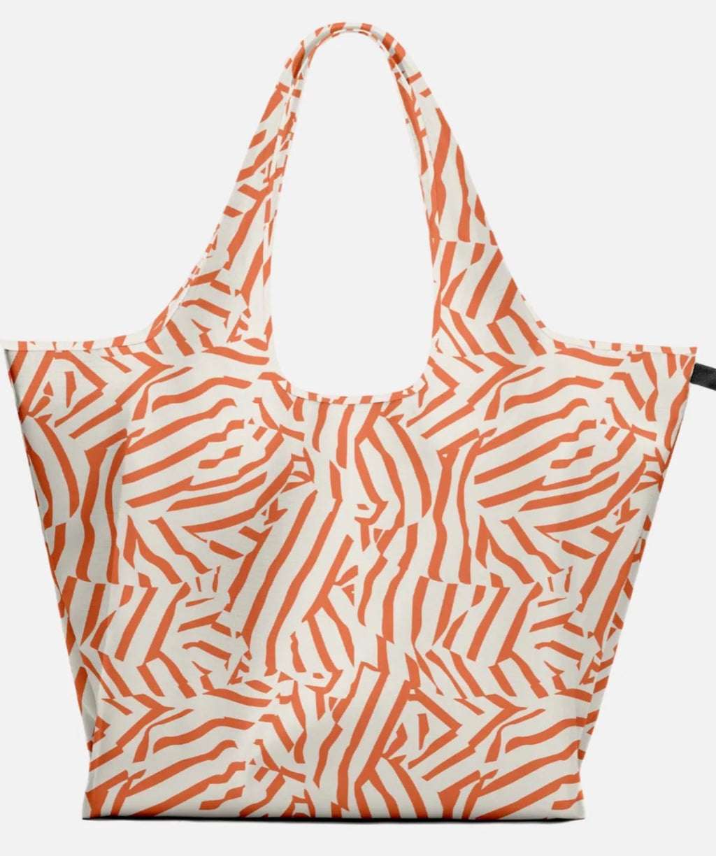 A reusable tote bag with a bold orange and off-white abstract wavy pattern, shown against a plain light gray background.