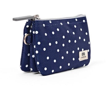 A navy blue canvas coin pouch with white polka dots, featuring a silver zipper, a small metal ring, and a white brand label on the bottom right.