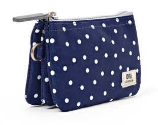 A navy blue canvas zip pouch with white polka dots, featuring a silver zipper, a wristlet strap, and a small white brand label on the front.